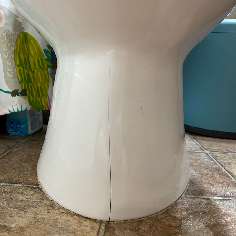 Cracked toilet base showing damage that requires toilet replacement